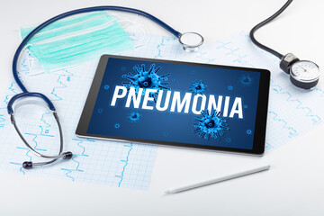 Tablet pc and doctor tools on white surface with PNEUMONIA inscription, pandemic concept
