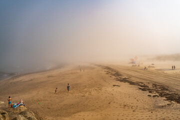 Fototapeta na wymiar Magische-Mystische Strandlandschaft. Nebel, Fog, Mist, Wolken am Stand mit Menschen in der Distanz und Blick auf den ewigen Ozean.