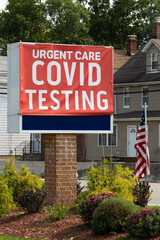 Fototapeta na wymiar sign at a covid testing site with white lettering on a red sign with the United States flag beside it