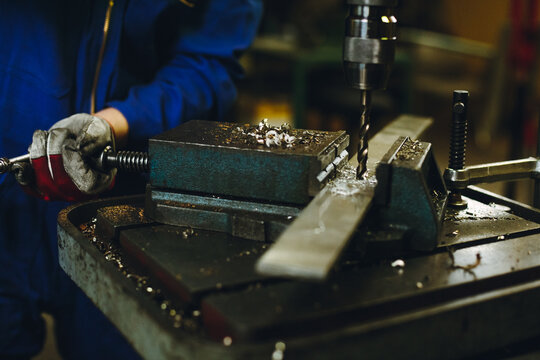 detail of a metal worker drilling a metal plate