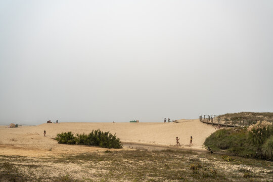 Magische-Mystische Strandlandschaft. Nebel, Fog, Mist, Wolken am Stand mit Menschen in der Distanz und Blick auf den ewigen Ozean.