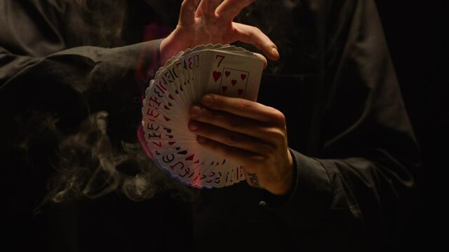 Close-up of a Magician Hand Performing Card Trick . Burning card on black Background with smoke . Card Mechanic holding flaming card in hand . Shot on ARRI Alexa cinema camera in Slow Motion 