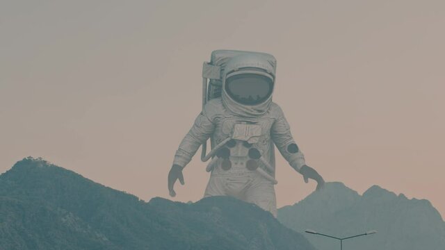 A Giant Alien Astronaut In Search Of Life On Earth. Astronaut Among The Mountains In The City