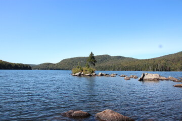 Naklejka premium Adirondack lake with island containing rocks and trees