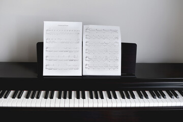 Empty black piano with notes in front of white wall