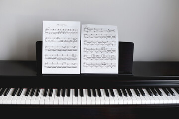 Empty black piano with notes in front of white wall