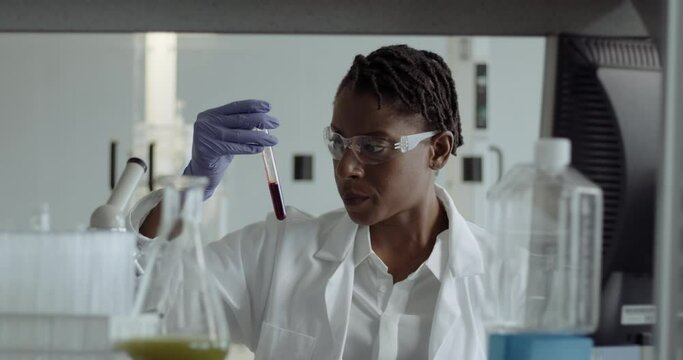 Female Laboratory Scientist Conducts Experiment in Science lab looking at blood sample with Coronavirus