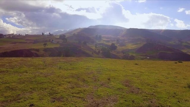 Drone footage taken in Ecuador&rsquo;s Ca&ntilde;ar province, near Ingapirca and the Andes mountain range.  Shot moves up over the green grassy hillside, lit with sunlight diffused by clouds.