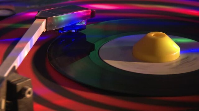 45 RPM vinyl record spinning on a turntable with flashing lights.