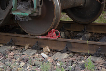 Red rail shoe under the wheel of the carriage on the rails
