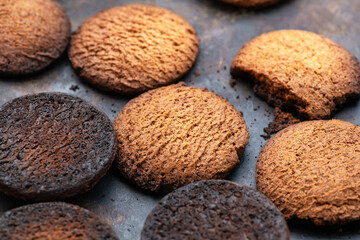 Fototapeta na wymiar Burnt cookies. Burnt oatmeal cookies lie on a black baking sheet.