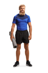 Full length portrait of a bearded man with moustache holding an exercise mat