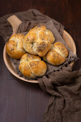 Homemade Kaiser Rolls Topped with Poppy Seeds in a Round Wooden Bowl on a Wooden Table