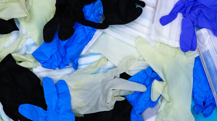 Multicolored crumpled latex surgical gloves and medical protective masks lie in disarray. Flat lay. Used remedies against the Covid-19 virus