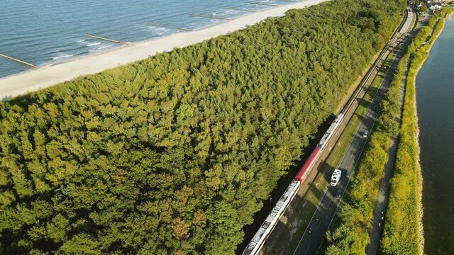 Aerial Cinematic view on train between green forest Baltic Sea and guld of Gdansk, Kuznica Poland