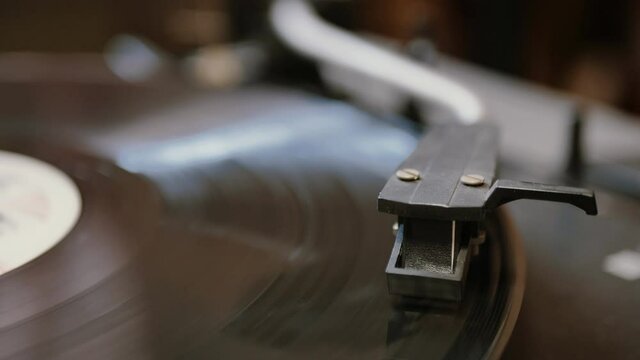 hands placing the vintage turntable on a spinning vinyl record. the vinyl record is spinning. the needle plays on a vintage vinyl record