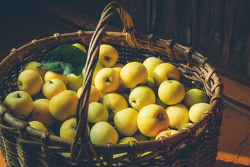 green apples in a knitted basket on a wooden background