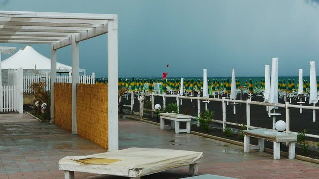 Summer thunderstorm with cloudy sky. In the resort of a beach in Puglia, the umbrellas have been closed and the sunbeds stacked up