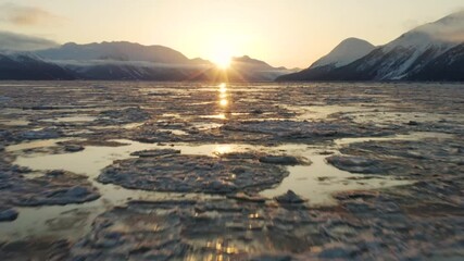 Perfect cinematic aerial flying over ice sheets tilt up camera revealing sunrise - Powered by Adobe