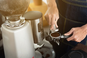 Hand of barista man holding coffee tamper with grind coffee for making coffee for customers