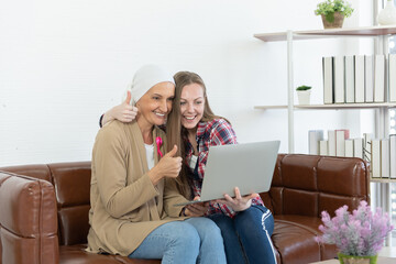The senior breast cancer patient and her daughter use computer laptop to conversation by webcam, cancer concept