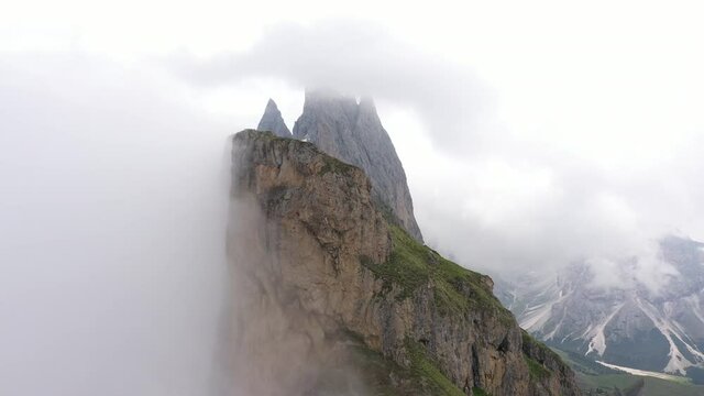 Rotating aerial view of spectacular mountain ridge, contrast between cragged rock formations and lush green Summer pastures, Seceda mountains in the Dolomites Italy Europe
