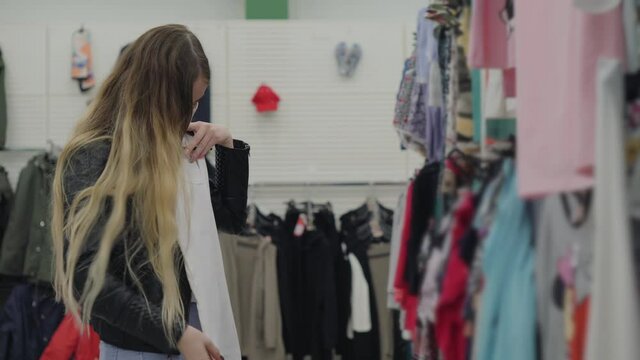 Young woman in medical mask buying undershirt in hypermarket
