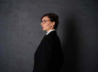 Side view of woman in black jacket on dark background