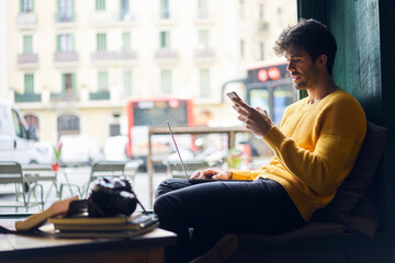 Young handsome ethnic man browsing smartphone in creative workspace
