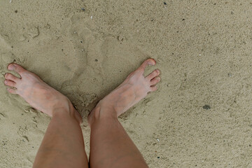 Feet naked barefoot without shoes burrow in the sand on a sandy beach, white skin and toes make...