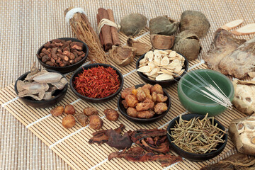 Traditional Chinese herbal medicine with acupuncture needles & herb & spice selection on bamboo. Alternative health care concept.