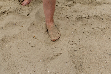 Feet naked barefoot without shoes burrow in the sand on a sandy beach, white skin and toes make movements