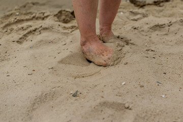 Feet naked barefoot without shoes burrow in the sand on a sandy beach, white skin and toes make movements