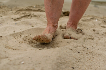 Feet naked barefoot without shoes burrow in the sand on a sandy beach, white skin and toes make movements