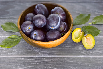 blue plums in a wooden bowl. background with plums. plum trees close - up on a wooden background.