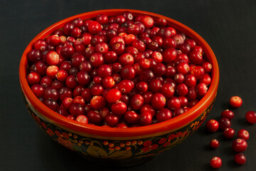 Cranberries in wooden bowl on the dark background