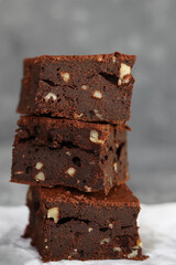 Front view of homemade chocolate brownie with walnut on gray background.