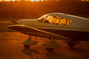 Landed small four-seater airplane at sunset background.