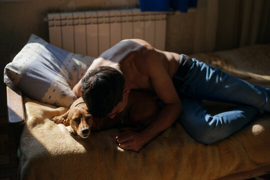 a guy at home lies on a bed with a dog