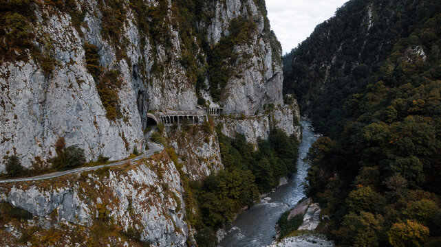 Old abandoned road passes by the mountain cliff with a river downside