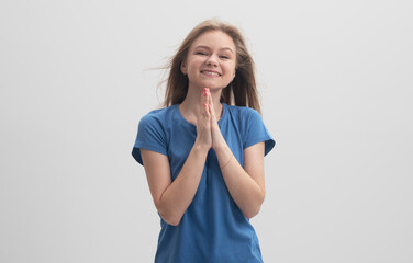 Happy cheerful pleasant looking female pleads for something and keeps palms pressed together,...