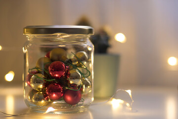 Christmas decorations inside a glass jar and warm lights in the background.
