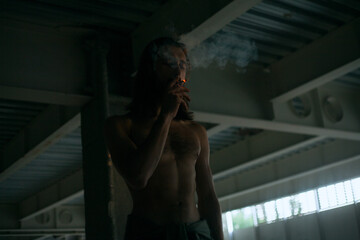 guy with a naked torso. smokes in the dark