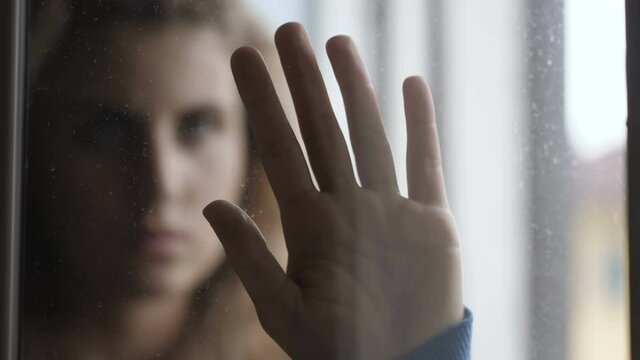 young woman puts his hand on the glass as if he wants to push the camera away