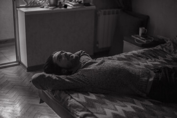 the guy melancholy looks at the ceiling while lying on the bed