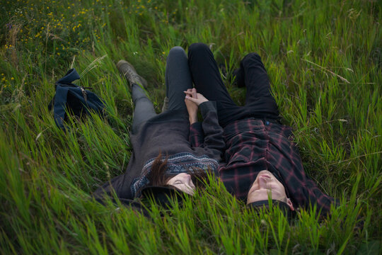 stylish couple are lying in the green grass