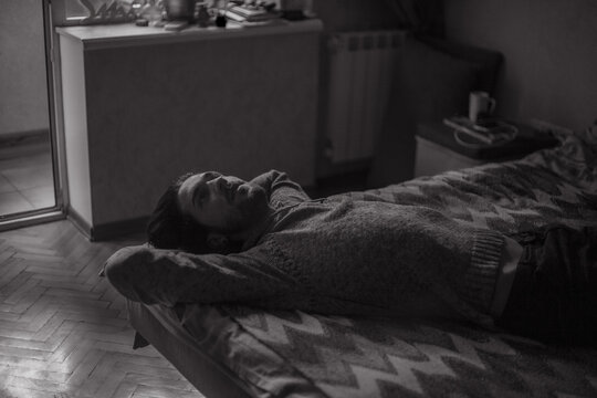 the guy melancholy looks at the ceiling while lying on the bed