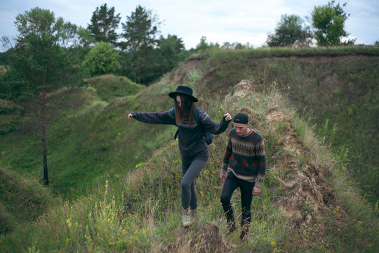 a guy and a girl walking on green hills