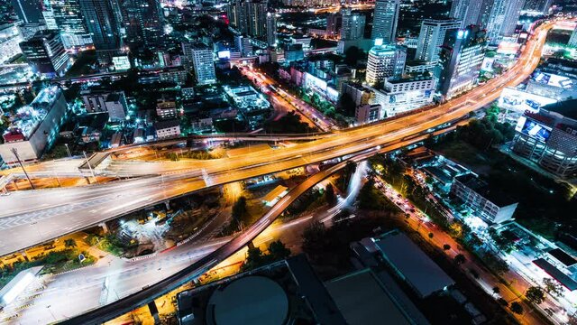Time-lapse of car traffic transportation on highway road, toll gate at night. Cityscape view with construction crane on building. Urban transport lifestyle, Asian city life. High angle view