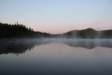Fototapeta premium Mist rising from the warm lake at dawn
